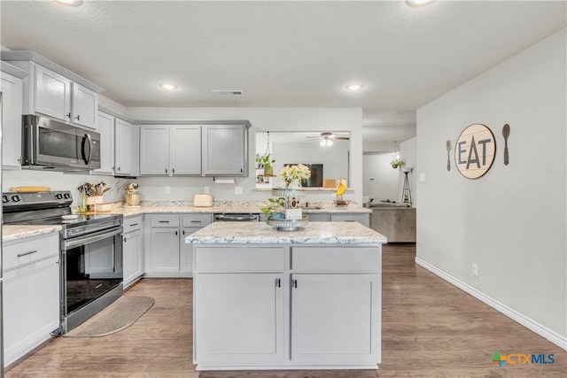 6402 Castle Gap Dr, Killeen, TX 76549 - kitchen featuring stainless steel appliances, a ceiling fan, wood finished floors, a kitchen island, and baseboards