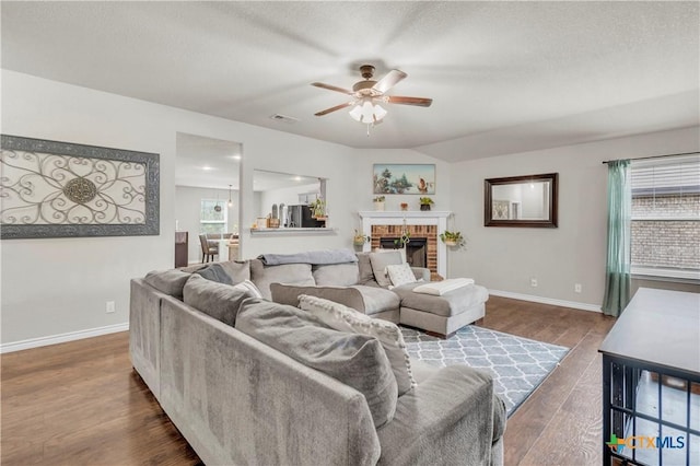 6402 Castle Gap Dr, Killeen, TX 76549 - living area with a ceiling fan, baseboards, dark wood-type flooring, a brick fireplace, and a textured ceiling