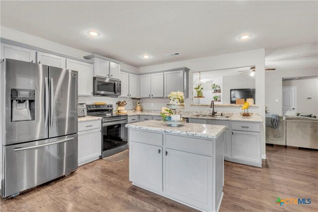 6402 Castle Gap Dr, Killeen, TX 76549 - kitchen featuring stainless steel appliances, a sink, a kitchen island, wood finished floors, and recessed lighting