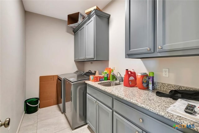 clothes washing area featuring washing machine and clothes dryer, light tile patterned floors, cabinet space, and a sink