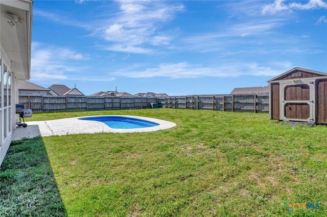 view of yard featuring a storage unit, an outbuilding, a fenced backyard, and a patio area