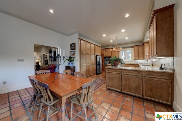 tiled dining space with a chandelier, ornamental molding, and sink