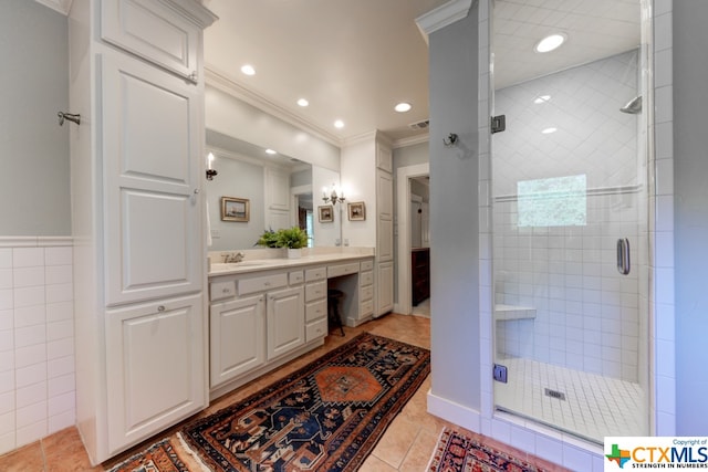 bathroom with tile patterned flooring, an enclosed shower, vanity, tile walls, and ornamental molding