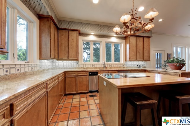 kitchen featuring crown molding, sink, a notable chandelier, a center island, and a breakfast bar area