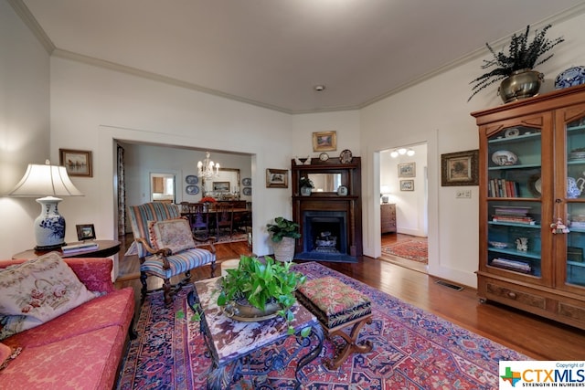 living room with wood-type flooring, an inviting chandelier, and ornamental molding