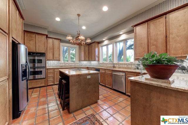 kitchen with stainless steel appliances, sink, pendant lighting, a notable chandelier, and a center island