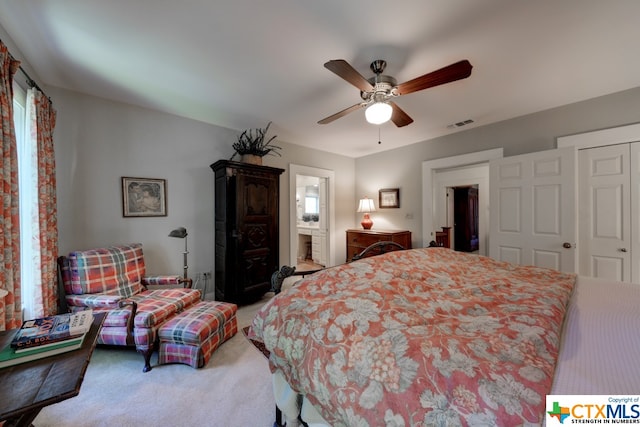 bedroom featuring ceiling fan, light colored carpet, ensuite bathroom, and a closet