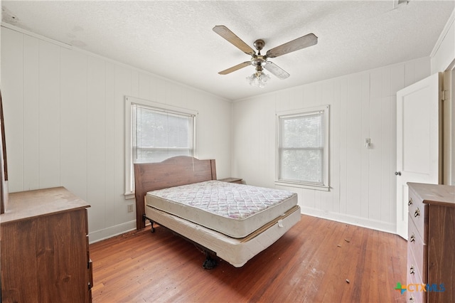 bedroom featuring hardwood / wood-style flooring, ceiling fan, multiple windows, and a textured ceiling