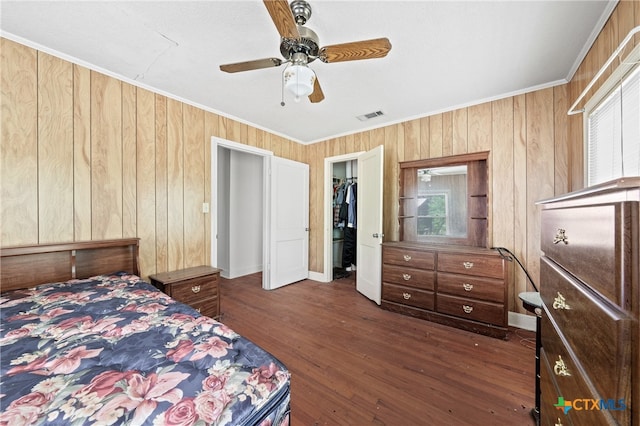 bedroom with dark wood-type flooring, ornamental molding, ceiling fan, a closet, and a spacious closet