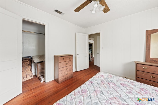 bedroom featuring dark wood-type flooring, ceiling fan, crown molding, and a closet