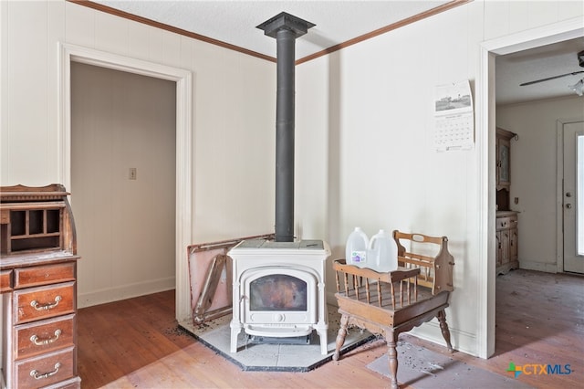 details with hardwood / wood-style floors, ceiling fan, a wood stove, and ornamental molding