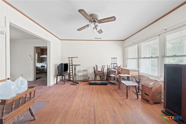 sitting room with a textured ceiling, hardwood / wood-style floors, ornamental molding, and ceiling fan