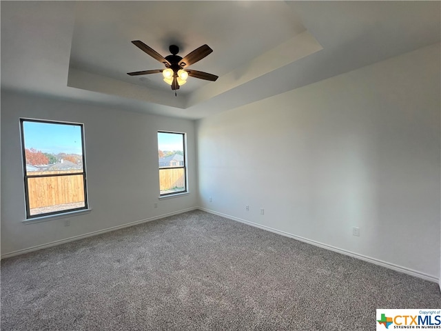 carpeted empty room with a tray ceiling and ceiling fan