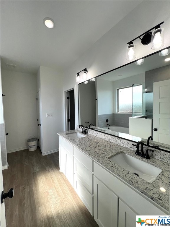 bathroom featuring wood-type flooring, vanity, and a tub