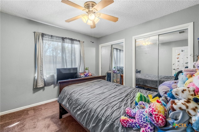 carpeted bedroom with ceiling fan, a textured ceiling, and two closets