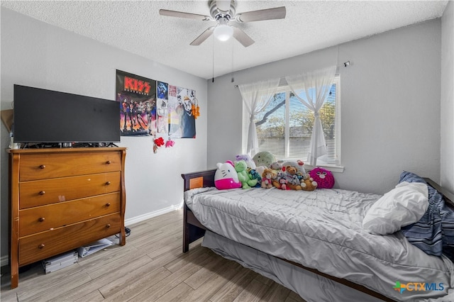 bedroom featuring ceiling fan, a textured ceiling, and light wood-type flooring