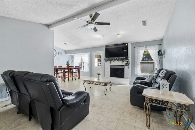 tiled living room with ceiling fan, a fireplace, a textured ceiling, and a wealth of natural light