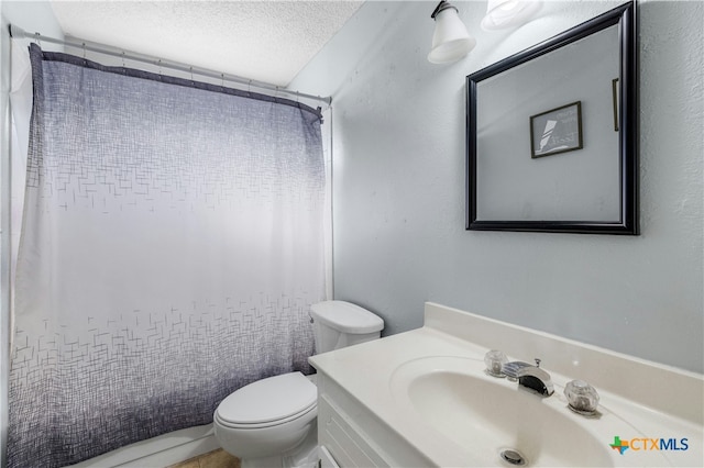 bathroom featuring a shower with shower curtain, vanity, toilet, and a textured ceiling