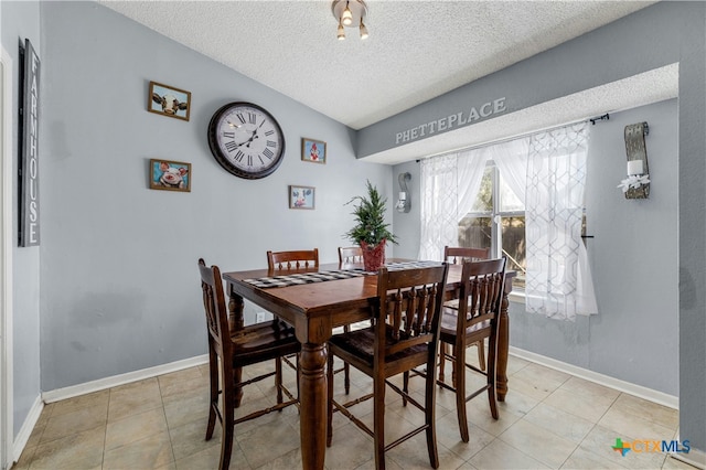 dining space featuring a textured ceiling, vaulted ceiling, and light tile patterned flooring