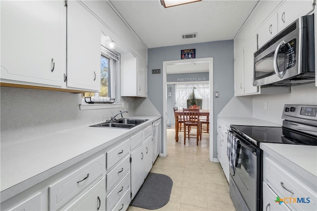 kitchen featuring light tile patterned flooring, appliances with stainless steel finishes, white cabinetry, and sink