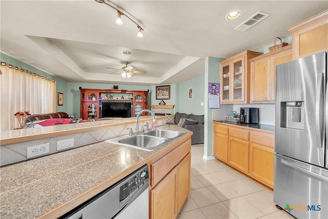 kitchen with light brown cabinets, stainless steel fridge with ice dispenser, open floor plan, a tray ceiling, and a sink