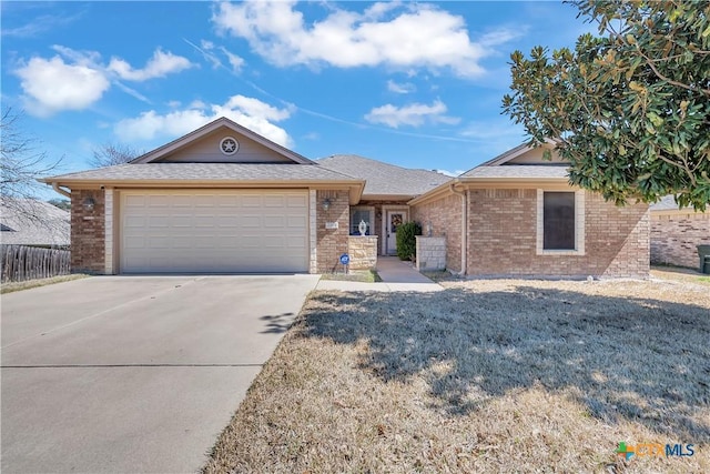 single story home with fence, driveway, an attached garage, a shingled roof, and brick siding