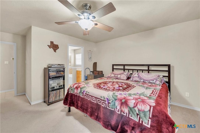 bedroom with light colored carpet, ensuite bathroom, baseboards, and ceiling fan