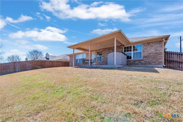 rear view of property featuring brick siding, a fenced backyard, a patio area, and a yard