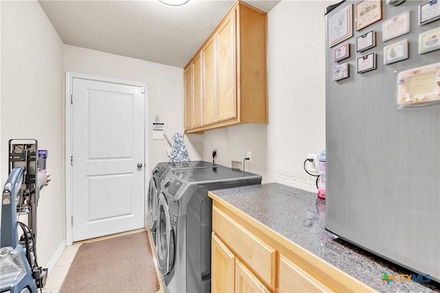 washroom featuring light tile patterned floors, cabinet space, a textured ceiling, and washer and clothes dryer