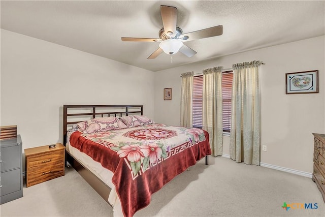 bedroom featuring ceiling fan, a textured ceiling, baseboards, and light carpet