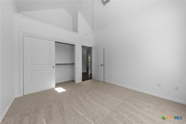 unfurnished bedroom featuring carpet, a closet, visible vents, high vaulted ceiling, and baseboards