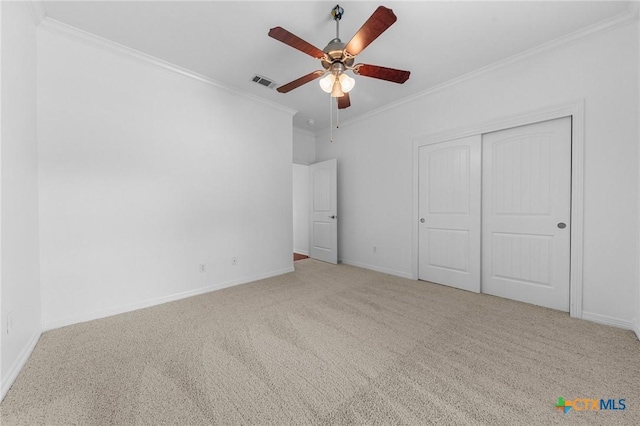 unfurnished bedroom with carpet floors, a closet, visible vents, ornamental molding, and baseboards