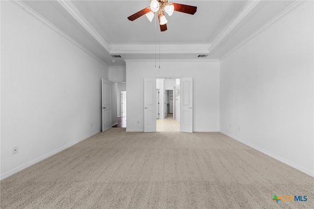 unfurnished bedroom with ornamental molding, a tray ceiling, baseboards, and light colored carpet