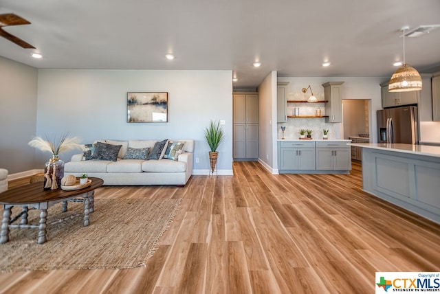 living room with ceiling fan and light wood-type flooring