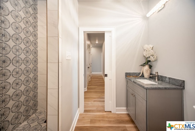 bathroom featuring vanity, hardwood / wood-style floors, and a tile shower