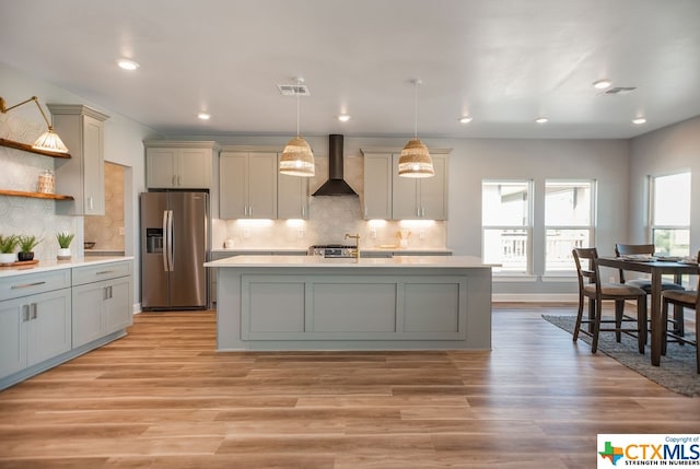 kitchen with pendant lighting, gray cabinetry, wall chimney range hood, and appliances with stainless steel finishes