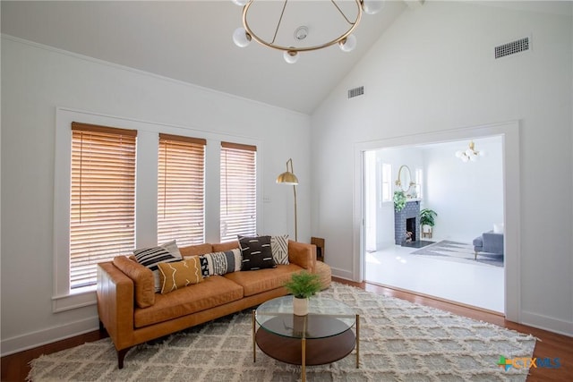 living area with high vaulted ceiling, a chandelier, visible vents, and a fireplace