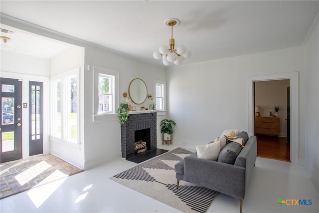 living area with a brick fireplace, an inviting chandelier, ornamental molding, and visible vents