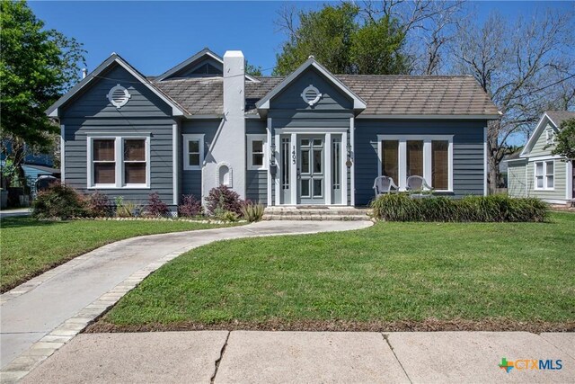view of front of home with a chimney and a front lawn