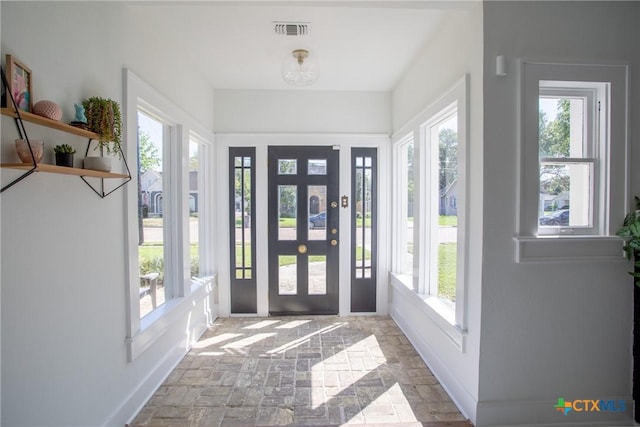 foyer entrance featuring visible vents, stone finish flooring, and baseboards