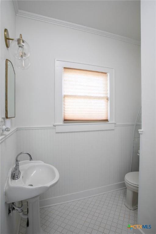 bathroom featuring baseboards, ornamental molding, wainscoting, and toilet