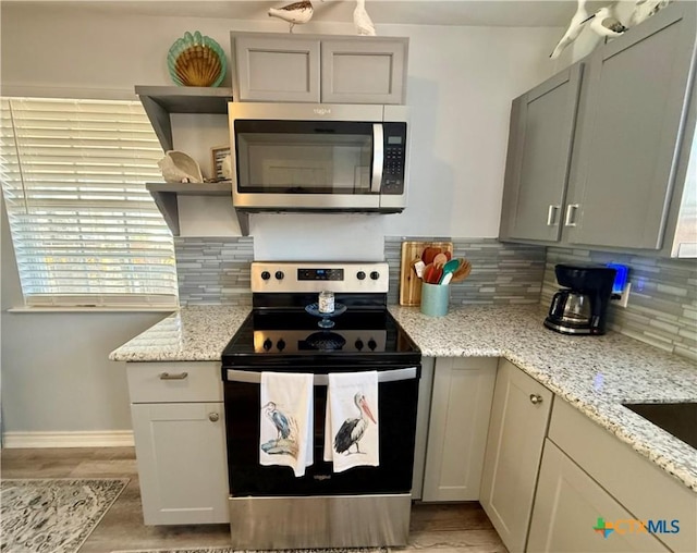 kitchen with tasteful backsplash, stainless steel appliances, gray cabinets, and light stone counters