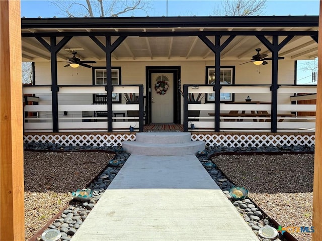 view of exterior entry with ceiling fan and covered porch