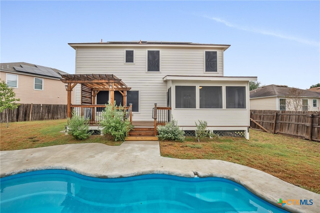 back of property with a pool side deck, a pergola, a lawn, and a patio area