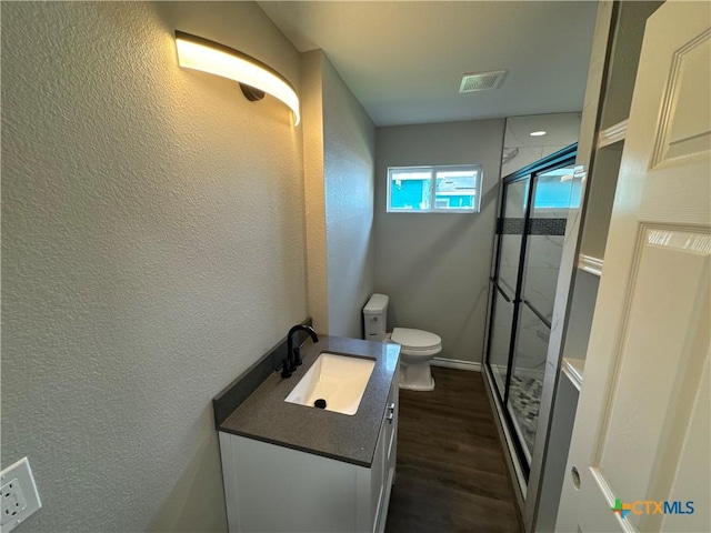 3004 Mayfair Dr, Victoria, TX 77901 - full bath with toilet, vanity, a shower stall, a textured wall, and wood finished floors