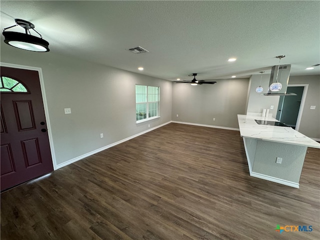 unfurnished living room featuring ceiling fan, a wealth of natural light, a textured ceiling, and dark hardwood / wood-style floors