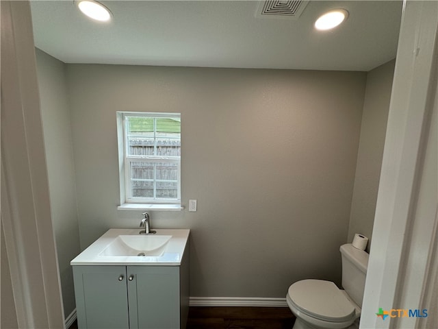 bathroom with toilet, vanity, and hardwood / wood-style floors