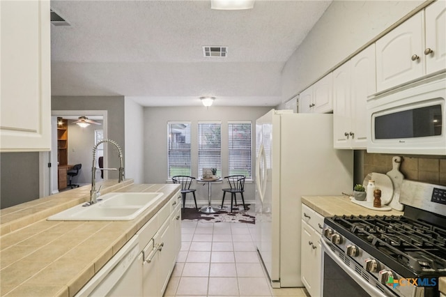 7401 Napier Trl, Austin, TX 78729 - kitchen with white appliances, tile countertops, white cabinetry, light tile patterned floors, and tasteful backsplash