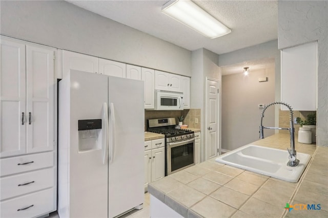 7401 Napier Trl, Austin, TX 78729 - kitchen with white appliances, white cabinets, tile counters, backsplash, and a textured ceiling