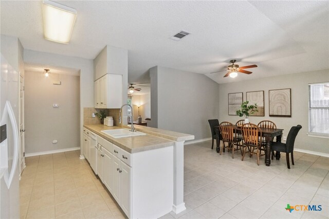 7401 Napier Trl, Austin, TX 78729 - kitchen with a ceiling fan, a peninsula, light countertops, and light tile patterned floors